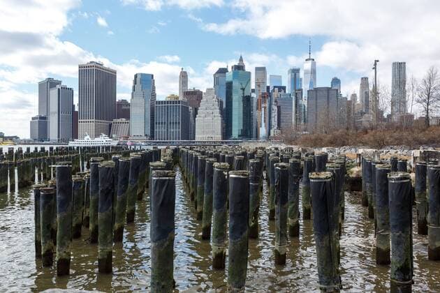 USA, United States of America, New York, New York, 16.03.2018: Blick vom Brooklyn Bridge Park und Pfähle stillgelegter Hafenanlagen auf die Skyline von Manhattan und den Finanzdistrikt