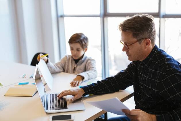 Businessman using laptop at desk in office with son sitting next to him model released Symbolfoto property released  EBSF02096