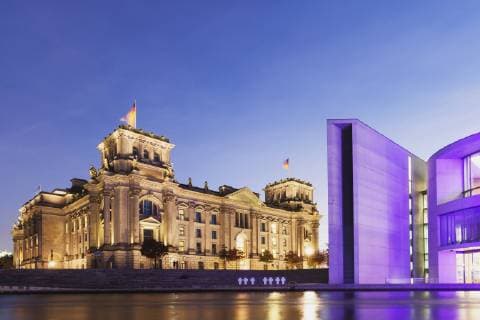 Germany, Berlin, Regierungsviertel, Reichstag building with German flags and Paul-Loebe-Building at Spree river in the evening  GWF05442