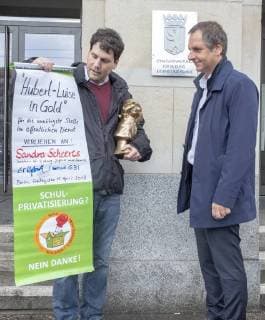 Negativ Zwerg Deutschland, Berlin, 13.04.2018, Negativpreis für Ausschreibung Oberregierungsrat Öffentlichkeitsarbeit Taskforce Schulbau verliehen, Verleihung Negativpreis Hubert-Luise in Gold (Zwerg) für die unnötigste Stelle im öffentlichen Dienst, durch Aktive von GiB (Gemeingut in BürgerInnenhand) der Bildungssenatorin Sandra Scheeres, Thorsten Metter, Leiter der Pressestelle der Senatsverwaltung für Bildung (rechts) nahm den Preis stellvertretend entgegen, die Laudatio hielt Carl Waßmuth (links) , Sprecher von Gemeingut in BürgerInnenhand (GiB), vor der Senatsverwaltung für Bildung, Jugend und Familie, Â