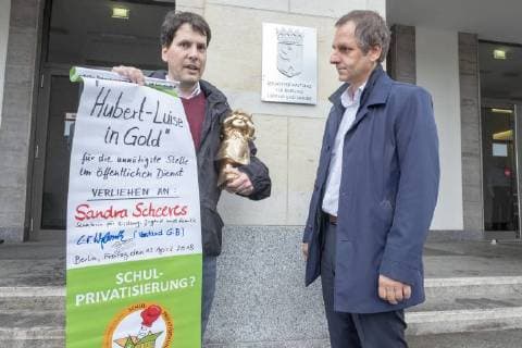 Negativ Zwerg Deutschland, Berlin, 13.04.2018, Negativpreis für Ausschreibung Oberregierungsrat Öffentlichkeitsarbeit Taskforce Schulbau verliehen, Verleihung Negativpreis Hubert-Luise in Gold (Zwerg) für die unnötigste Stelle im öffentlichen Dienst, durch Aktive von GiB (Gemeingut in BürgerInnenhand) der Bildungssenatorin Sandra Scheeres, Thorsten Metter, Leiter der Pressestelle der Senatsverwaltung für Bildung (rechts) nahm den Preis stellvertretend entgegen, die Laudatio hielt Carl Waßmuth (links) , Sprecher von Gemeingut in BürgerInnenhand (GiB), vor der Senatsverwaltung für Bildung, Jugend und Familie, Â