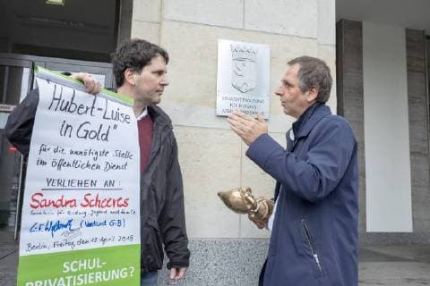 Negativ Zwerg Deutschland, Berlin, 13.04.2018, Negativpreis für Ausschreibung Oberregierungsrat Öffentlichkeitsarbeit Taskforce Schulbau verliehen, Verleihung Negativpreis Hubert-Luise in Gold (Zwerg) für die unnötigste Stelle im öffentlichen Dienst, durch Aktive von GiB (Gemeingut in BürgerInnenhand) der Bildungssenatorin Sandra Scheeres, Thorsten Metter, Leiter der Pressestelle der Senatsverwaltung für Bildung (rechts) nahm den Preis stellvertretend entgegen, die Laudatio hielt Carl Waßmuth (links) , Sprecher von Gemeingut in BürgerInnenhand (GiB), vor der Senatsverwaltung für Bildung, Jugend und Familie, Â