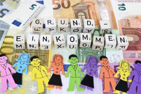 BuchstabenwÃ¼rfel formen das Wort Grundeinkommen auf Geldscheinen