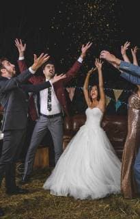 Cheerful wedding couple and friends raising their arms while confetti falling over their heads on a night party outdoors model released Symbolfoto property released  DAPF00955