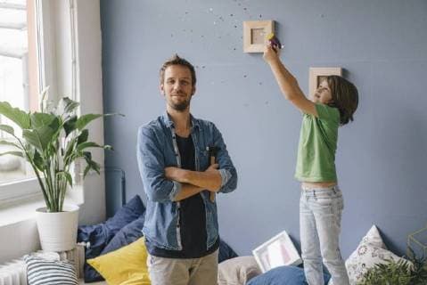 Son blowing confetti over proud father holding hammer at home model released Symbolfoto property released  KNSF03642