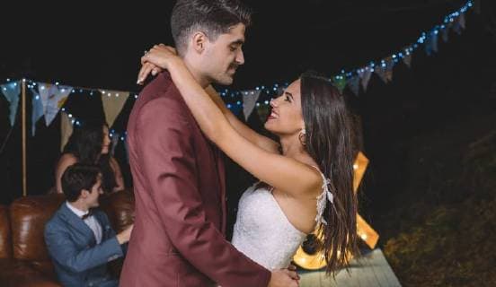 Romantic wedding couple embracing on a night field party with their friends in the background model released Symbolfoto property released  DAPF00938