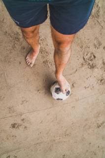 Low section of man with footall on the beach model released Symbolfoto  KKAF00898