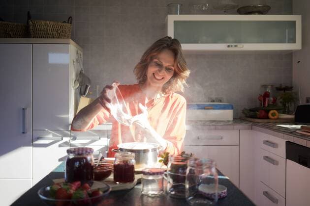 Smiling woman making strawberry jam in kitchen at home model released Symbolfoto property released  MOEF00933