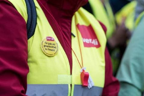 Deutschland, Berlin - 24.04.2018 F??r gute und gesunde Arbeit bei Amazon steht auf einer Brosche w??hrend der Demonstration gegen die Verleihung des Axel Springer Award 2018 an Amazon-Gr??nder Jeff Bezos f??r sein vision??res Unternehmertum . Mitarbeiter des Unternehmens demonstrierten unter dem Motto Make Amazon Pay again gegen den Axel Springer Award den nach Angaben des Medienunternehmens herausragende Pers??nlichkeiten, die in besonderer Weise innovativ sind, M??rkte schaffen und ver??ndern und sich ihrer gesellschaftlichen Verantwortung stellen erhalten. Gewerkschaften kritisieren die schlechten Arbeitsbedingungen in Amazons Logistik-Zentren die sie f??r nicht preisw??rdig erachten. Germany, Berlin - 24.04.2018 For good and healthy work at Amazon is written on a brooch during the demonstration against the awarding of the Ax