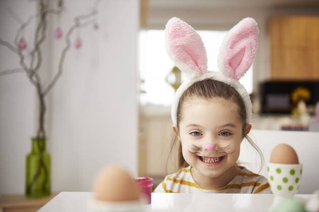 Portrait of smiling girl with bunny ears sitting at table with Easter eggs model released Symbolfoto property released  ABIF00160