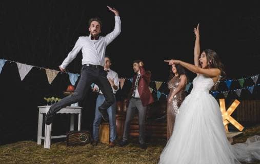 Surprised bride looking at man jumping on a night field party with friends model released Symbolfoto property released  DAPF00942
