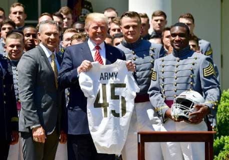 President Donald Trump receives a jersey from Army Black Nights team captain John Voit (2nd-R), quarterback Ahmad Bradshaw (R) and head coach Jeff Monken at a ceremony where Trump presented the Commander-in-Chief?s Trophy to the U.S. Military Academy football team, in the Rose Garden at the White House in Washington, D.C. on May 1, 2018. The Commander-in-Chief Trophy is presented each year to the season s winner of the American college football competition among the three service academies.  WAP20180501304 KEVINxDIETSCH