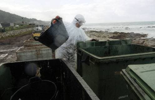 Freiwillige Helfer der spanischen Umweltorganisation Tragsa reinigen am Donnerstag (12.12.2002) einen Küstenabschnitt bei Mougas (Galicien), der vom Oel des gesunkenen Tankers Prestige verseucht ist. Zur Reinigung stehen ihnen nur einfachste Hilfsmittel zur Verfügung. Es fehlt überall an Geräten um die Strände vom Oel zu säubern. Deswegen gerät die Regierung um Ministerpräsident José-Maria Aznar immer mehr unter Druck.