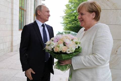 SOCHI, RUSSIA â€“ MAY 18, 2018: Russia s President Vladimir Putin (L) gives flowers to Germany s Chancellor Angela Merkel ahead of a meeting at Bocharov Ruchei residence. Mikhail Klimentyev Russian Presidential Press and Information Office TASS  TS08003A