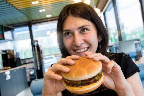MOSCOW, RUSSIA â€“ MAY 17, 2018: A woman eating a burger with a football bun at a Gazprom Neft filling station. Sergei Bobylev TASS  TS0801D6