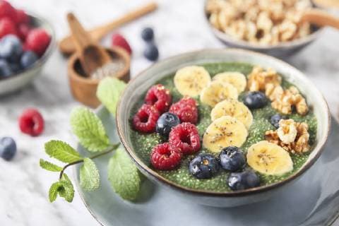 Buddha bowl of green chia pudding with slices of banana, blueberries, raspberries and walnuts  RTBF01142