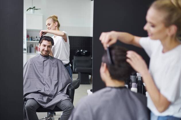 Smiling hairdresser combing man s hair model released Symbolfoto property released  ABIF00350