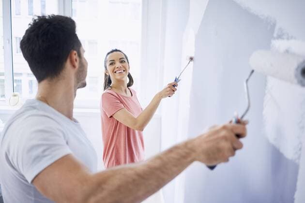 Happy couple painting wall in apartment together model released Symbolfoto property released  BSZF00426
