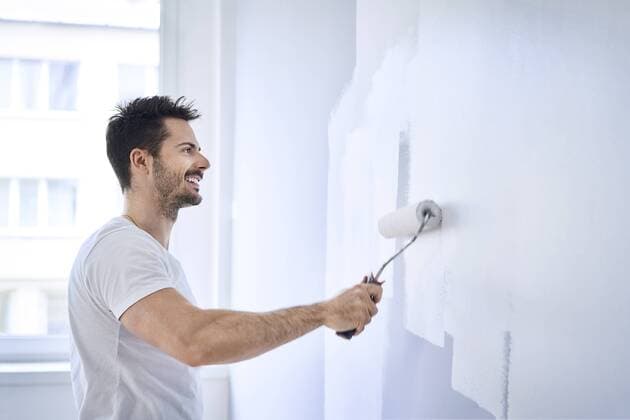 Smiling man painting wall in apartment model released Symbolfoto property released  BSZF00428