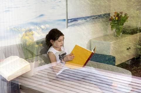 Girl sitting on the couch at home reading a book model released Symbolfoto property released  NEKF00040