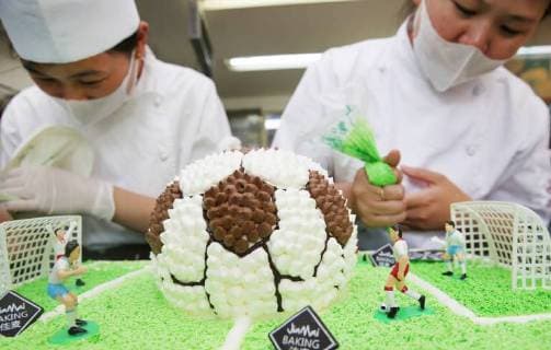 China: Football shaped cake Bakers make a World Cup themed cake at a bakery in Nantong, east China s Jiangsu Province. People can see football and football field at the cake. CHINA OUT Nantong Nantong China  XuxCongjun