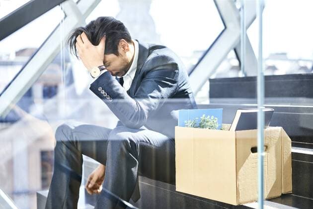 Depressed businessman sitting on stairs with belongings in cardboard box beside him model released Symbolfoto property released  BSZF00561