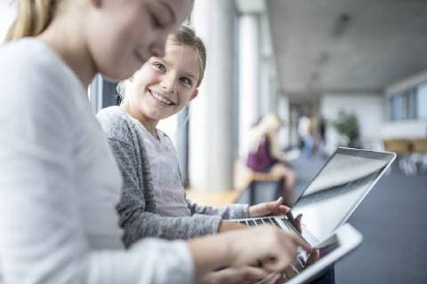 Happy schoolgirls with laptop and tablet on school corridor model released Symbolfoto property released  WESTF24175