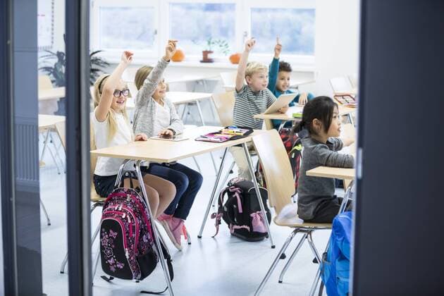 Happy pupils raising their hands in class model released Symbolfoto property released  WESTF24203