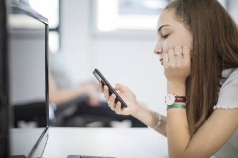 Teenage girl using cell phone in computer class model released Symbolfoto property released  ZEF15701