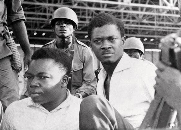 BRU62 - 20020205 - LEOPOLDVILLE, ZAIRE : (FILES) A picture dated of November 1960 shows Patrice Lumumba (R), Congolese Prime Minister, and Okito (L), Senate President, under the survey of Moise Tschombe s army guards, upon their arrest in Leopoldville. Tuesday 05 February 2002, Belgium officially presented excuses by the voice of Foreign Minister Louis Michel to the Congoleses, for its role in the death of Lumumba. The sons of Lumumba and Okito answered they were ready to forgive. PHOTO FILES  x830062x
