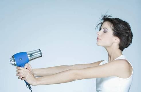 Woman holding out hair dryer, profile  Copyright: MatthieuxSpohn B74345501