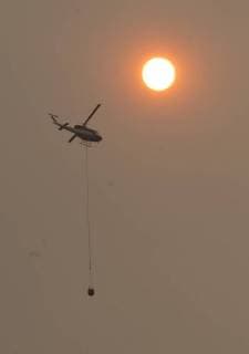 A helicopter dumps water along a ridge in Colusa County, California on August 7, 2018. The Mendocino Complex fire has become the largest in the state s history.  SXP2018080720 TERRYxSCHMITT