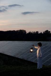 Girl standing in front of solar panels at twilight with old-fashioned lantern in hand  Copyright: OdilonxDimier B10061325