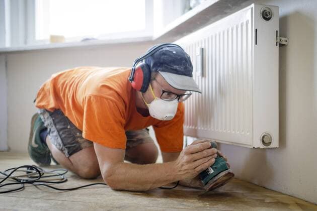 Ein Handwerker bearbeitet Holzdielen mit einer Schleifmaschine in einer Altbauwohnung. 24.07.2018, Berlin. Berlin Deutschland Copyright: xIngaxKjerx
