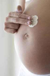 Woman applying moisturizer to pregnant belly, cropped  Copyright: FrédéricxCirou B08950413