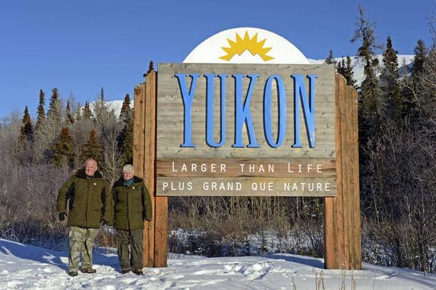 zwei Reisende am Schild der Region Yukon, Larger than Life, Plus Grand de Nature, Kanada, Yukon two travellers at the sign of region Yukon, Larger than Life, Plus Grand de Nature, Canada, Yukon BLWS489775 Copyright: xblickwinkel F.xBagyix