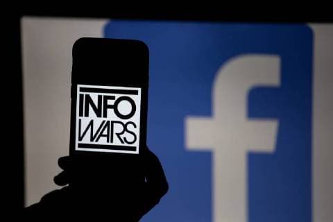 August 23, 2018 - Munich, Bavaria, Germany - The logo of Infowars is seen in the foreground while there the logo of Facebook in the background. The accounts of the extreme right and conspiracy theory portal Infowars have been banned from several social networks and even Youporn. Infowars is one of the media, that supports US-President Donald Trump most. The media was founded by Alex Jones. Munich Germany  - ZUMAn230 20180823_zaa_n230_291 Copyright: xAlexanderxPohlx