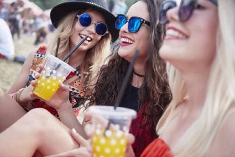 Friends drinking juice and sitting on meadow during music festival model released Symbolfoto  ABIF00598