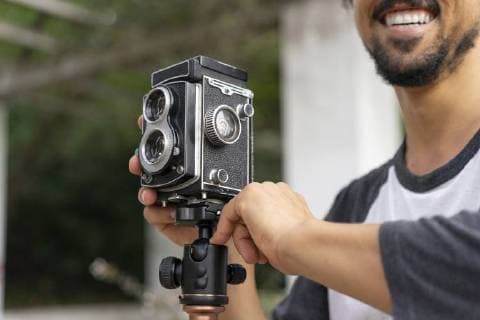 Close-up of happy young man using vintage camera model released Symbolfoto  AFVF00803