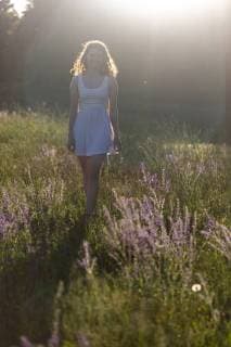 IMAGO Creative: Sommer, Abendspaziergang Young woman walking on flower meadow in the evening light model released Symbolfoto  SARF03810