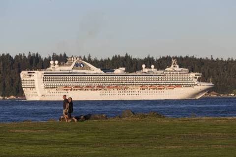 A couple strolls along a walkway on Tyee Spit while a incess cruiseline ship passes through Discovery Passage, Campbell River, Vancouver Island  acp110201 BoomerxJerritt