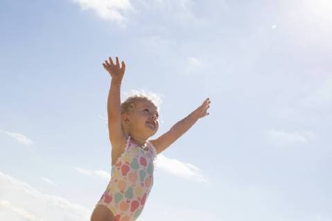 Little girl standing on beach with arms raised  Copyright: Anne-SophiexBost B88212531