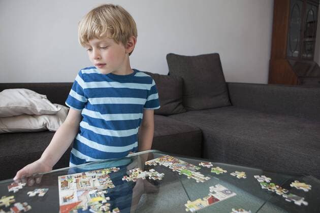Boy solving jigsaw puzzle on glass table in living room at home  Copyright: CarlxSmith fStopImages1361020