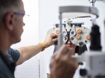 Optometrist examining young woman s eye model released Symbolfoto property released  CVF01032