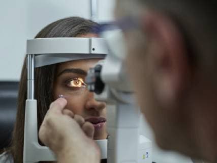 Optometrist examining young woman s eye, contact lens on index finger model released Symbolfoto property released  CVF01035