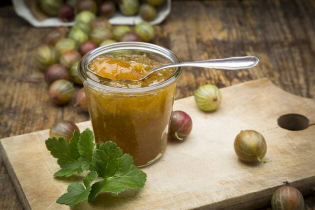 Jar of gooseberry jam and gooseberries on wooden board  LVF06268