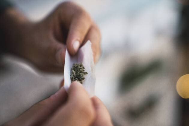 Young man rolling a joint model released Symbolfoto  KKAF01335