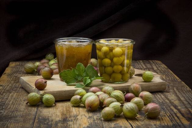 Jar of gooseberry jam, gooseberries and glass of preserved gooseberries on wood  LVF06270