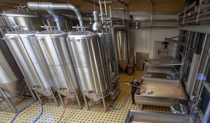 Insel-Hopping Ruegen , Der Leitende Brauer Sebastian Riekehr (26) schoepft Bitterstoffe und Brandhefe aus dem Gaerbottich in der Ruegener Insel-Brauerei in Rambin. Die Biersorte ist Insel-Kreide . Die Brauerei braut seit 2015 seltene Biere mit offener Gaerung und Flaschenreifung. -