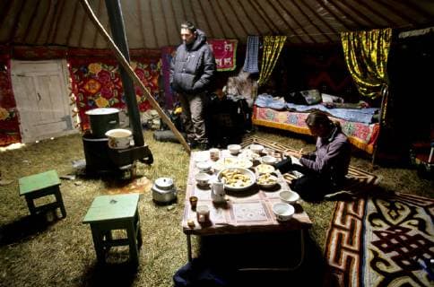 Taking a break from a snow storm inside a Kazakhs ger. The furniture inside a Kazakh Ger is always arranged in the same way: the stove resides in the middle, the beds -up to 6 singles- are placed against the walls, opposite to the door. A cupboard, one table, stools, and a some home-made colourful carpets completes the Ger., Tavanbogd National Park Mongolia model released Symbolfoto Copyright: OlivierxRenck 7282600022